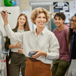 Teacher at a white board with smiling teems watching